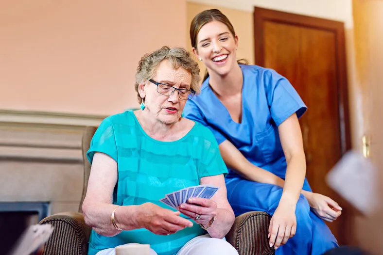 Betreuerin spielt mit einer Seniorin Karten